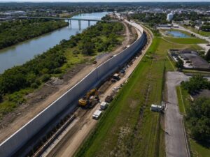 Aerial surveyor capturing high-resolution drone mapping for floodwall planning along a river to support elevation analysis, alignment, and construction design.